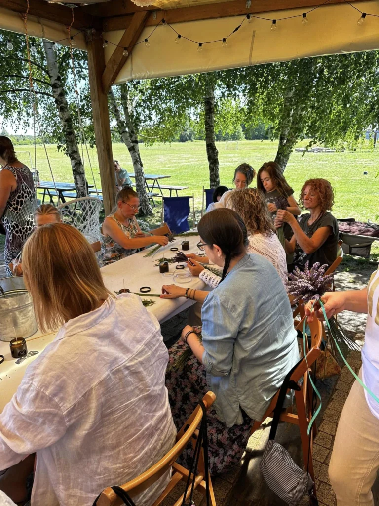Na zdjęciu widać stół i słuchaczy, ustawione na zewnątrz w letni dzień, w otoczeniu lawendy, podczas zajęć praktycznych na studiach podyplomowych.
